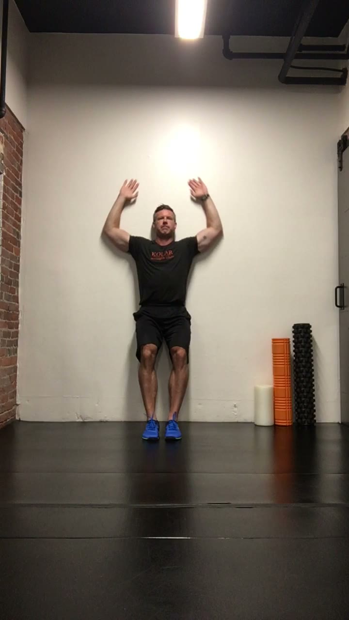 Brandon Kolar demonstrating a standing posterior wall slide mobility drill