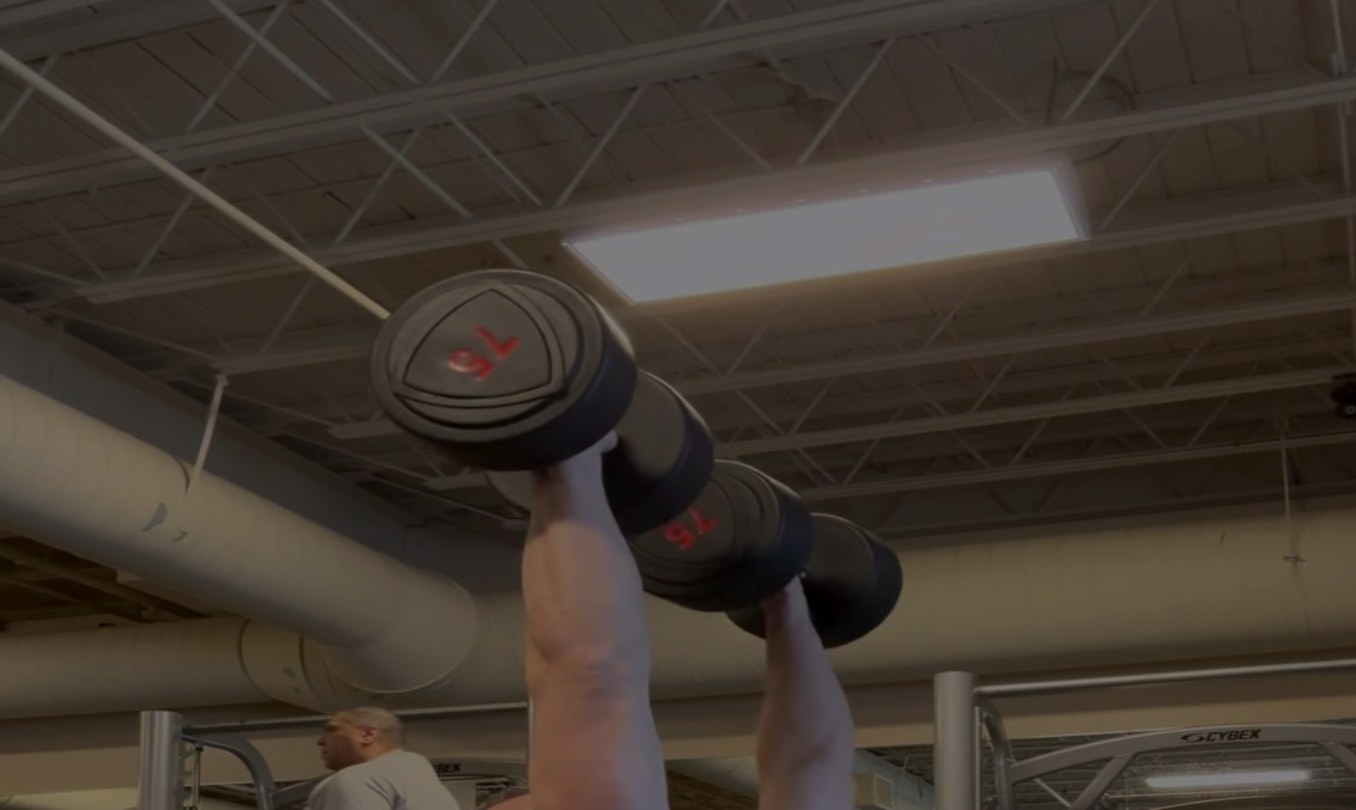 Brandon Kolar coaching a dumbbell overhead press